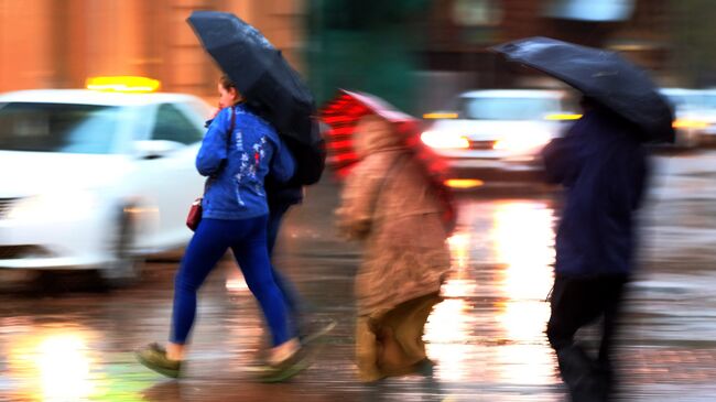 Пешеходы на улице в Москве во время сильного дождя. Архивное фото