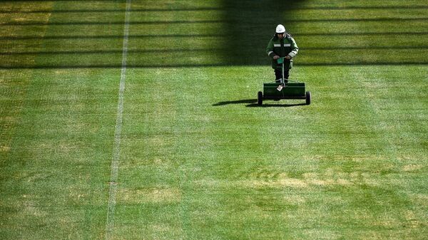 Работник косит траву на футбольном поле стадиона Волгоград Арена