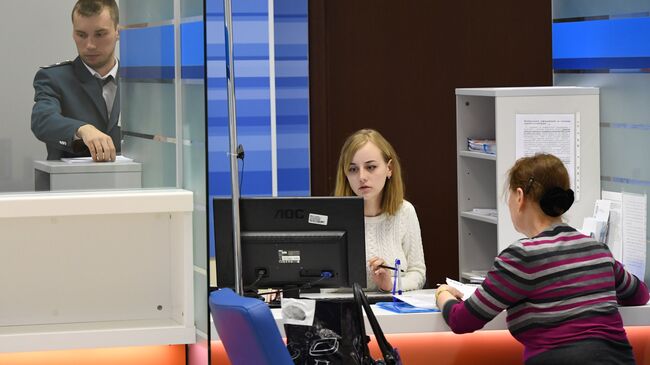 Сотрудники помогают посетительнице со сдачей налоговой отчетности в день открытых дверей в операционном зале инспекции Федеральной налоговой службы РФ в Москве