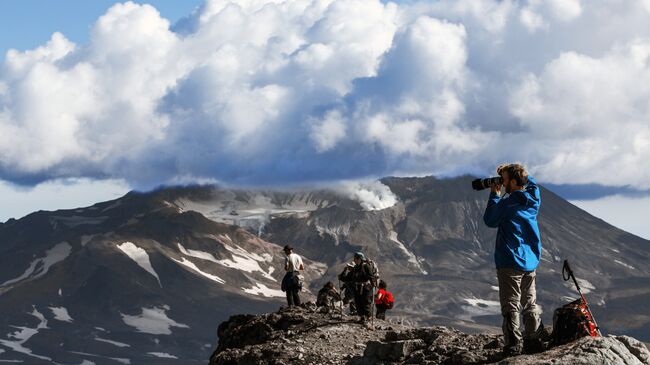 Туристы смотрят на вулкан Мутновский с вершины вулкана Горелого