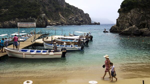Туристы на пляже Адриатического моря в деревне Палеокастрица на греческом острове Корфу