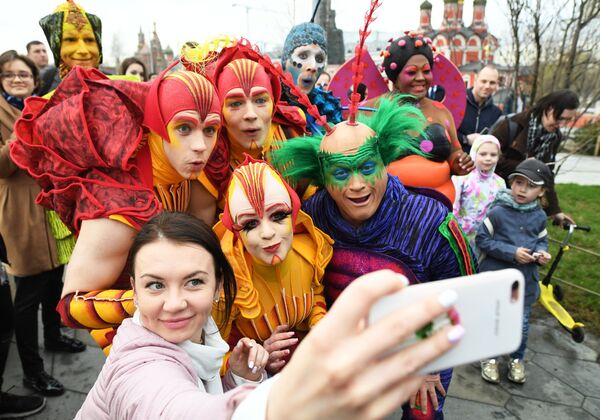 Артисты Cirque du Soleil делают селфи с девушкой на открытии летнего сезона в парке Зарядье в Москве