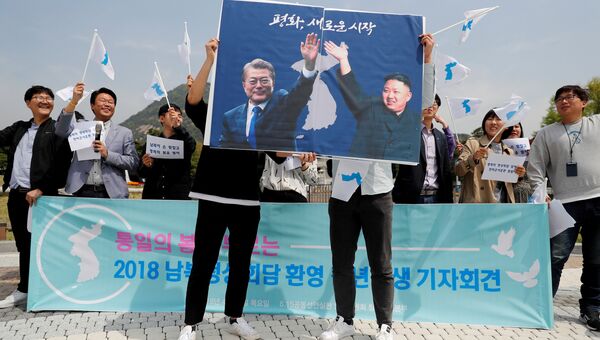 Студенты держат плакаты с фотографиями южнокорейского президента Мун Чжэ Ина и лидера КНДР Ким Чен Ына в Сеуле