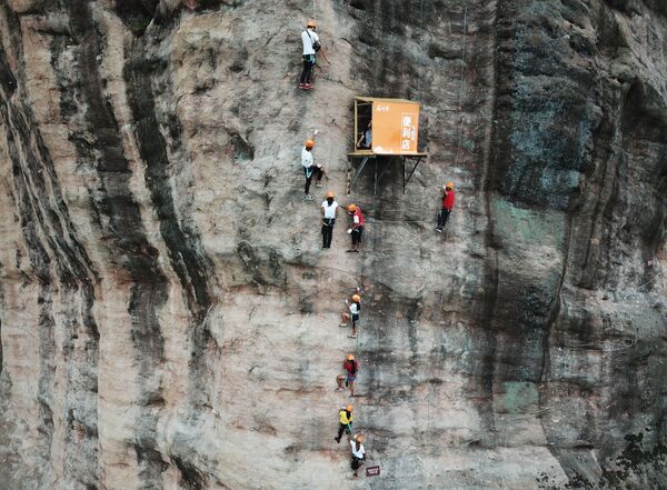Люди забираются на скалу в китайской провинции Хайнянь