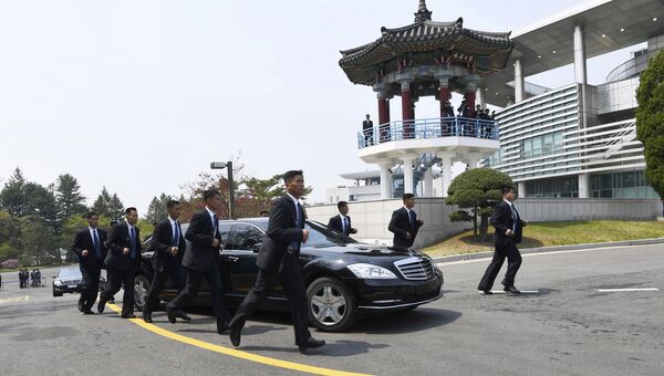 Сотрудники северокорейской службы безопасности рядом с автомобилем, в котором находится лидер Северной Кореи Ким Чен Ын. 27 апреля 2018