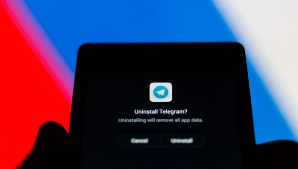 Логотип Telegram на экране смартфона на фоне флага РФ. Архивное фото