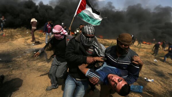 Раненый протестующий во время столкновений с израильскими войсками на границе Израиля и сектора Газа. 27 апреля 2018