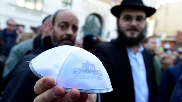 Мужчина показывает традиционную еврейскую кипу на мероприятии Berlin wears kippa в Берлине 