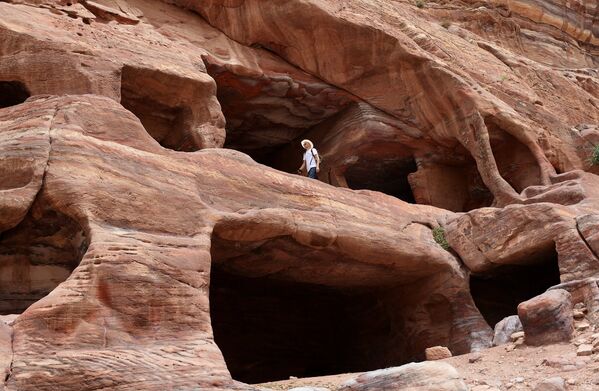 Турист осматривает дома-пещеры кочевников-бедуинов в древнем городе Петра в Иордании
