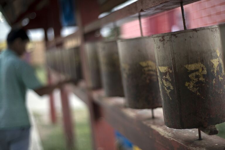 Верующий крутит молитвенные барабаны хурдэ на территории Иволгинского дацана в Бурятии Верующий крутит молитвенные барабаны хурдэ на территории Иволгинского дацана в Бурятии