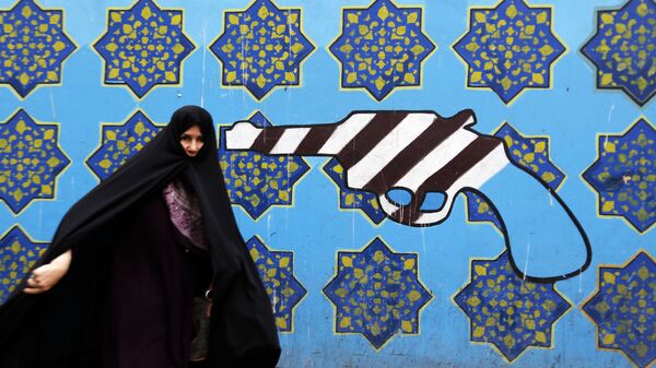 Иранская женщина проходит мимо граффити на стене бывшего посольства США в Тегеране