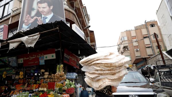 Женщина несет стопки хлеба на голове в Дамаске, Сирия. 10 мая 2018