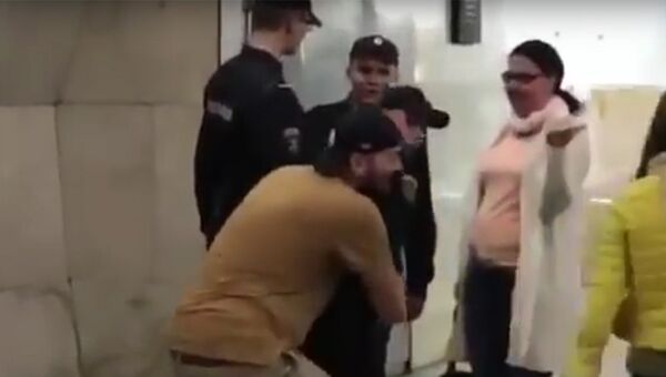 Стоп-кадр с видео, где мужчина несет сотрудника Росгвардии в руках по вестибюлю станции Сухаревская