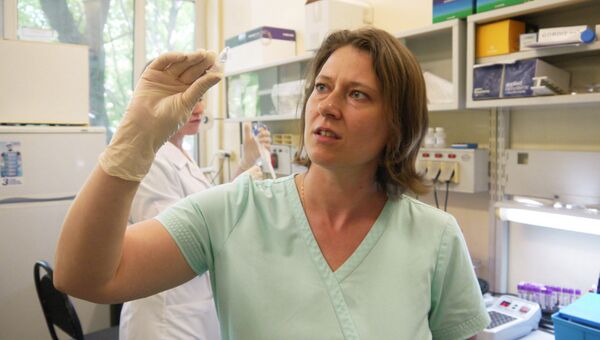 Заведующая лабораторией Ольга Щагина держит в руках пробирку с очищенным ДНК