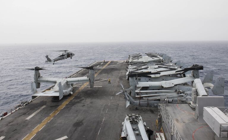 Американский палубный многоцелевой вертолет MH-60S Sea Hawk готовится к посадке на корабль USS Iwo Jima 6-го флота ВМС США. 23 марта 2018