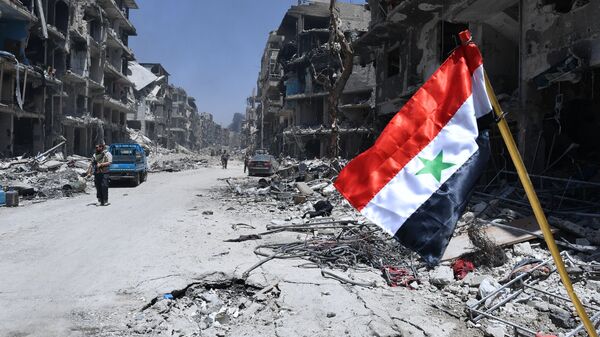 Флаг Сирии в освобожденном лагере палестинских беженцев Ярмук на юге Дамаска