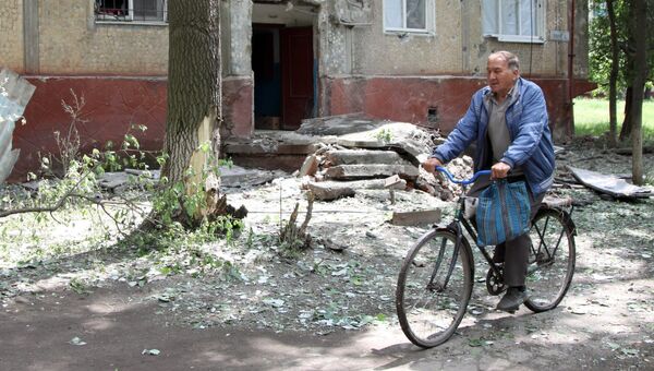 Мужчина едет на велосипеде во дворе жилого дома, пострадавшего в результате обстрела, в поселке Горловка Донецкой области. Архивное фото