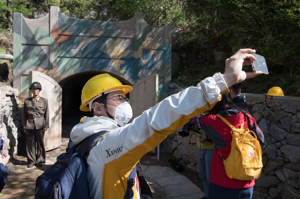 Журналисты из южной Кореи фотографируются у входа в одну из шахт во время закрытия ядерного полигона Пхунгери на севере КНДР