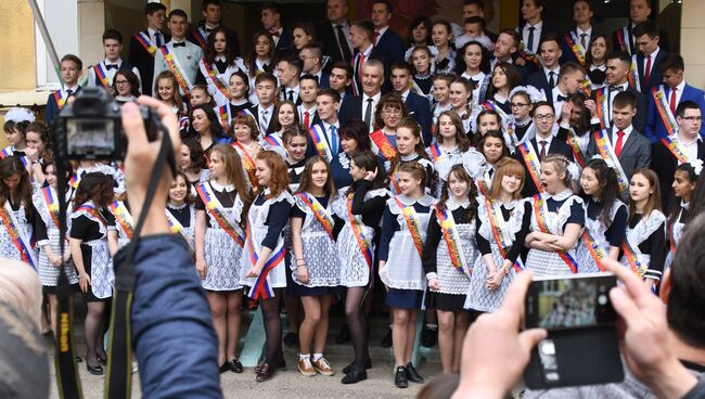 Выпускники фотографируются во время празднования последнего звонка. Архивное фото