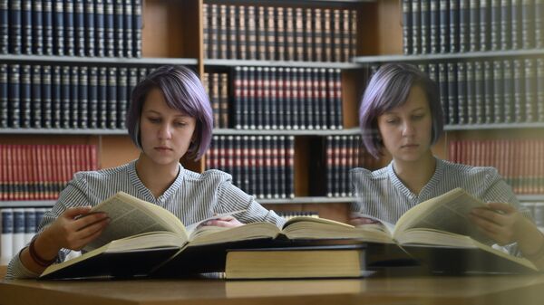 Девушка читает книгу в библиотеке. Архивное фото