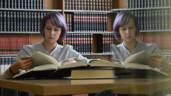 Девушка читает книгу в библиотеке
