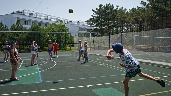 Дети играют в пионербол на спортивной площадке детского оздоровительного лагеря 
