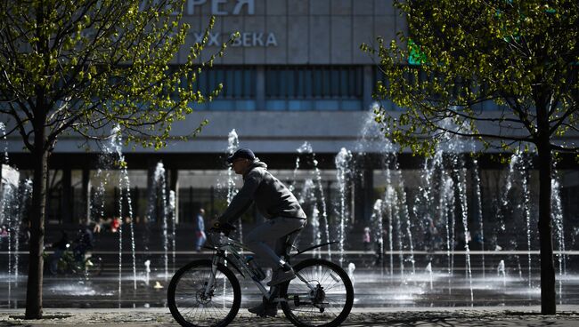 Мужчина катается на велосипеде в парке Музеон в Москве