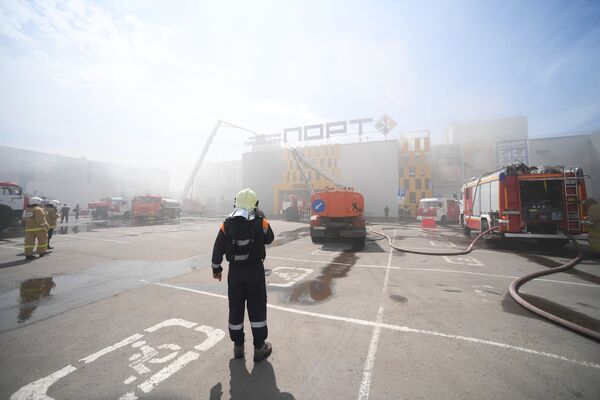 Сотрудники МЧС и пожарная техника перед зданием торгового центра Порт в Казани, где произошло возгорание