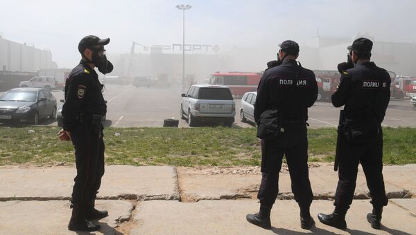 Сотрудники полиции и пожарная техника перед зданием торгового центра Порт в Казани, где произошло возгорание
