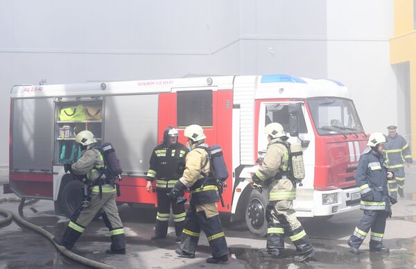 Сотрудники МЧС и пожарная техника перед зданием торгового центра Порт в Казани, где произошло возгорание