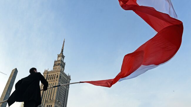 Мужчина держит польский флаг во время празднования Дня независимости в Варшаве. Архивное фото