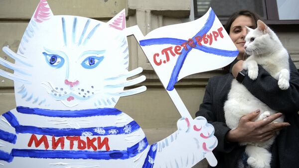 Девушка и эрмитажный кот-оракул Ахилл рядом с фигурой кота-футболиста, расписанной в рамках художественного марафона Моя любовь - футбол и кот! в Санкт-Петербурге