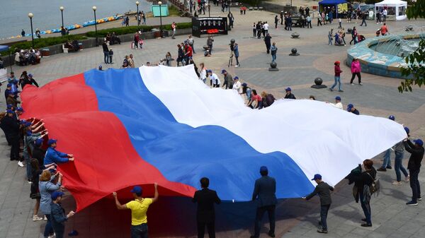 Люди держат флаг во время празднования Дня России