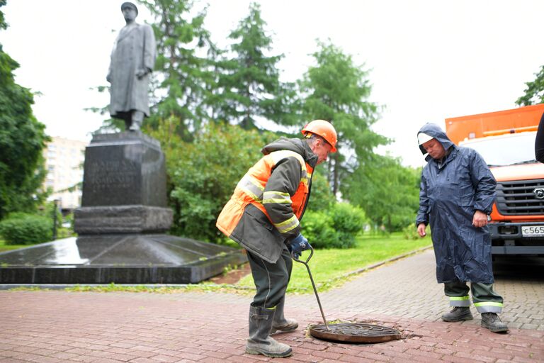 Сотрудники ГУП Мосводосток проверяют смотровой колодец Сотрудники ГУП Мосводосток проверяют смотровой колодец