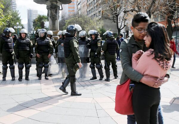 Пара обнимается возле сотрудников полиции во время акции протеста студентов в Ла-Пасе, Боливия