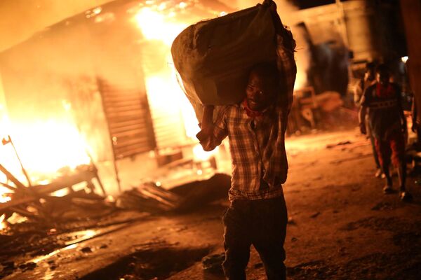 Мужчина несет мешок из огня на рынке в Порт-о-Пренсе, Гаити. 12 июня 2018 года
