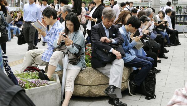 Люди сидят возле станции Йодоябаши после землетрясения