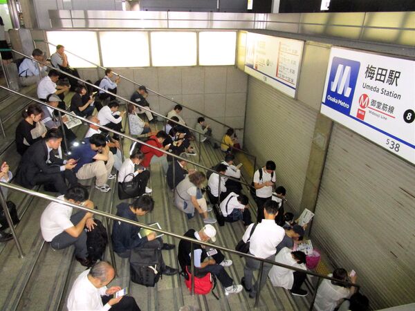Люди сидят возле станции после землетрясения в Осаке