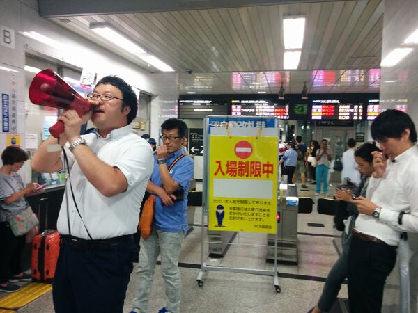 Сотрудник станции делает объявление пассажирам после землетрясения в Осаке