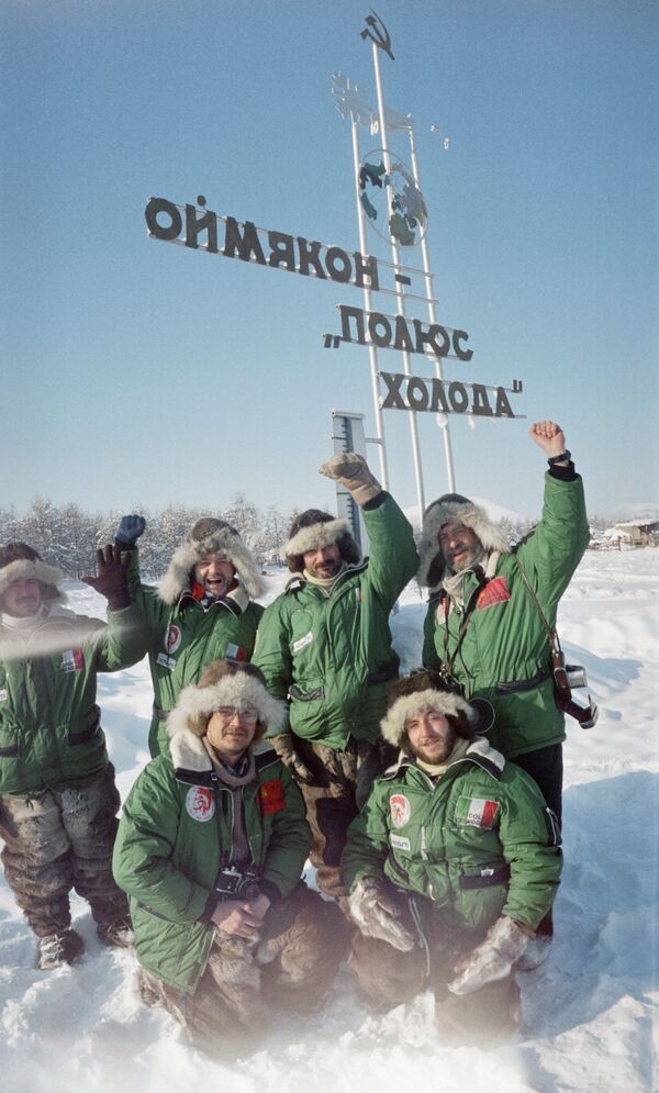 Туристы стоят у памятного знака Оймякон — полюс холода