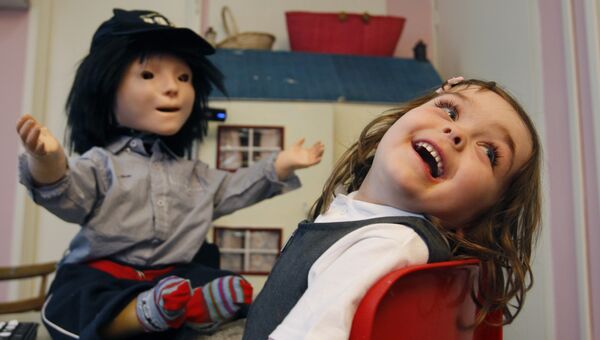 Девочка играет с социальным роботом Каспаром, созданным в качестве терапии для детей-аутистов