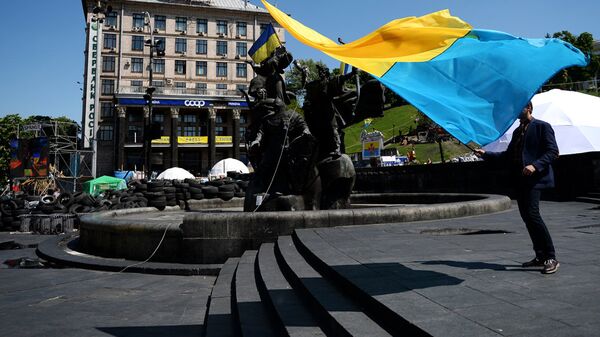 Молодой человек с украинским флагом у памятника основателям Киева на площади Независимости