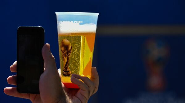 Болельщик фотографирует стакан пива с символикой чемпионата мира по футболу