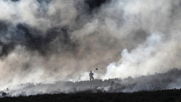 Пожарный тушит торфяник в Карвуде, Великобритания