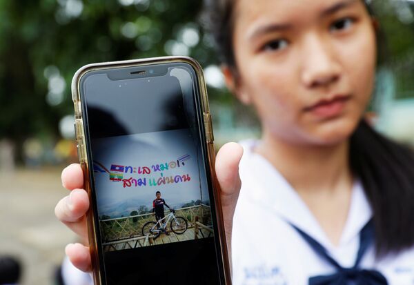 Студентка показывает фотографию своего одноклассника Прачака Сутама, 13 лет, члена футбольной команды, которая пропала без вести с тренером в затопленной пещере в Таиланде. 2 июля 2018 Студентка показывает фотографию своего одноклассника Прачака Сутама, 13 лет, члена футбольной команды, которая пропала без вести с тренером в затопленной пещере в Таиланде. 2 июля 2018