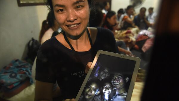 Родственница показывает фотографию найденных в пещере игроков детской футбольной команды и их тренера в Таиланде