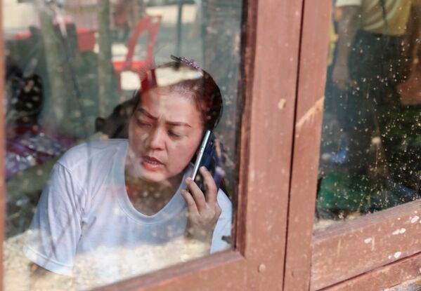 Родственница разговаривает по телефону неподалеку от пещерного комплекса, где были найдены дети