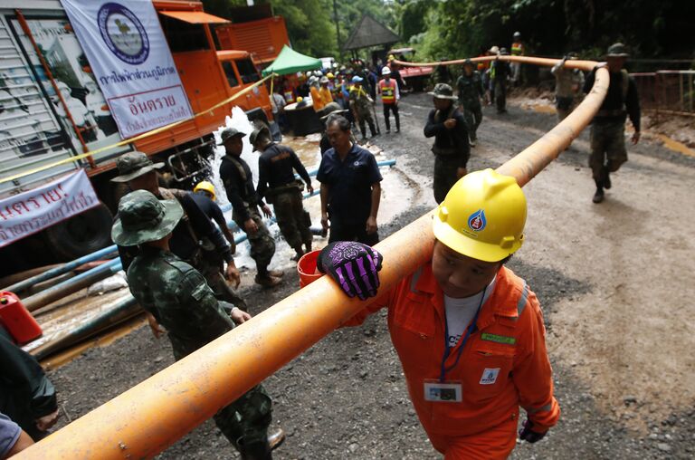 Рабочий держит трубу для откачки воды из пещеры Тхам Луанг в провинции Чиангмай
