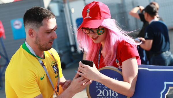 Болельщик сборной Бразилии и девушка-волонтер перед матчем группового этапа чемпионата мира по футболу. 27 июня 2018