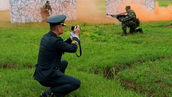 Корейский военнослужащий фотографирует солдат во время тренировки разведывательной роты на полигоне Сергеевский в Приморском крае. 4 июля 2018